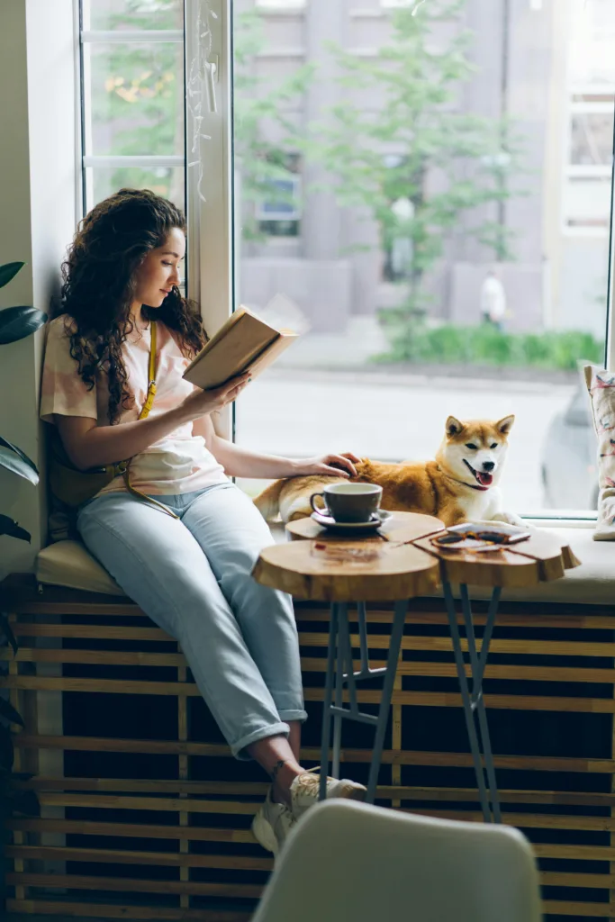 7 Creative Ways To Memorize Scripture. Woman sitting and reading her Bible in a window with a dog and coffee