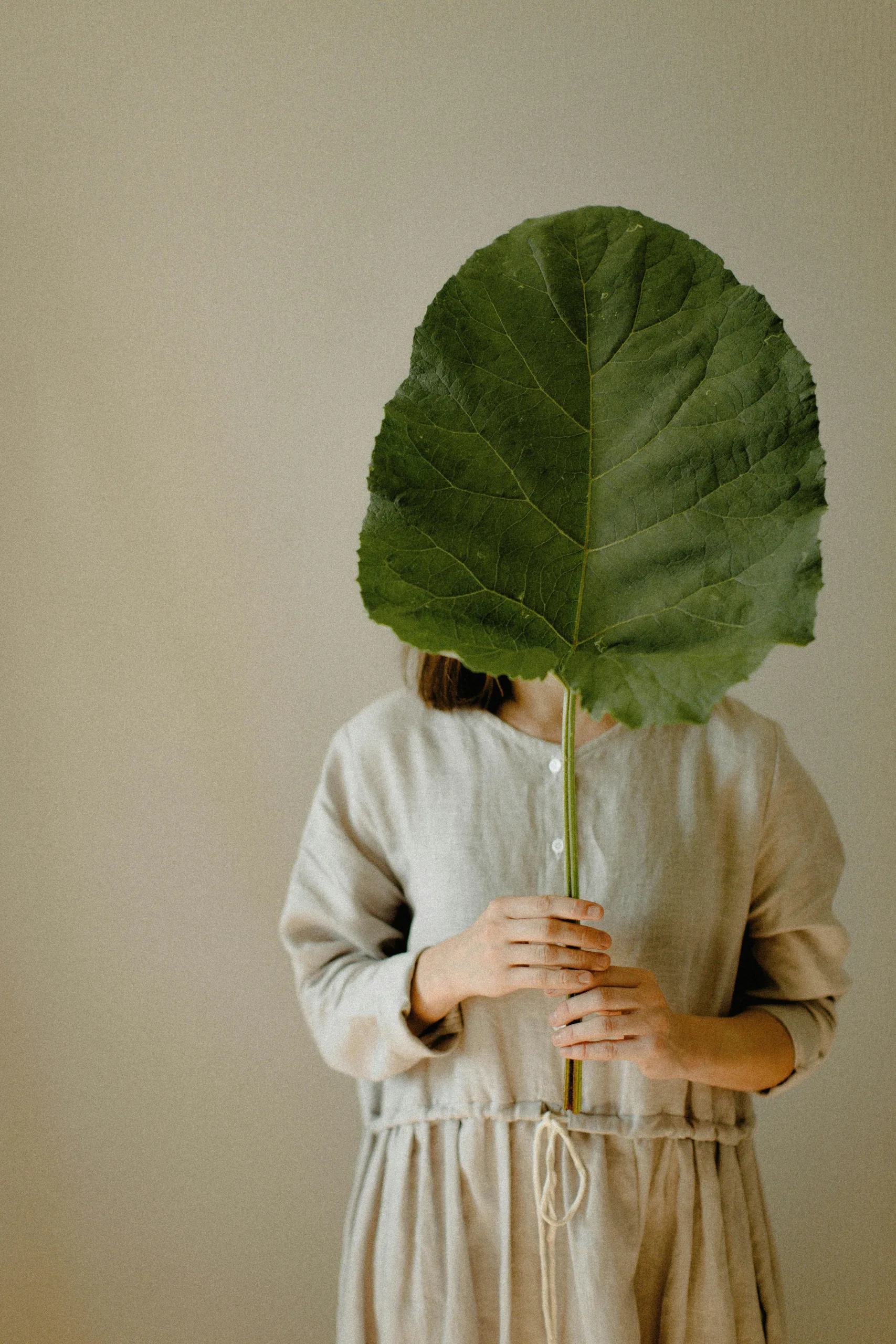 Girl covering face with leaf, overcoming shame