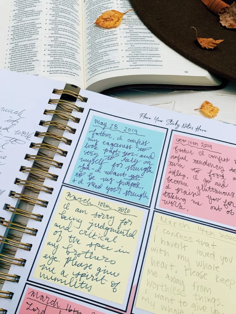 Open prayer journal displaying a heartfelt prayer to the Lord, placed beside an open Bible and a stylish woman’s hat on a table.