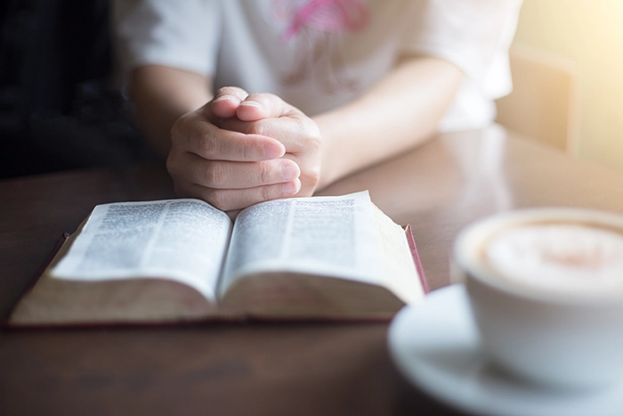 Christian woman in quiet prayer with Bible, hearing God's voice.