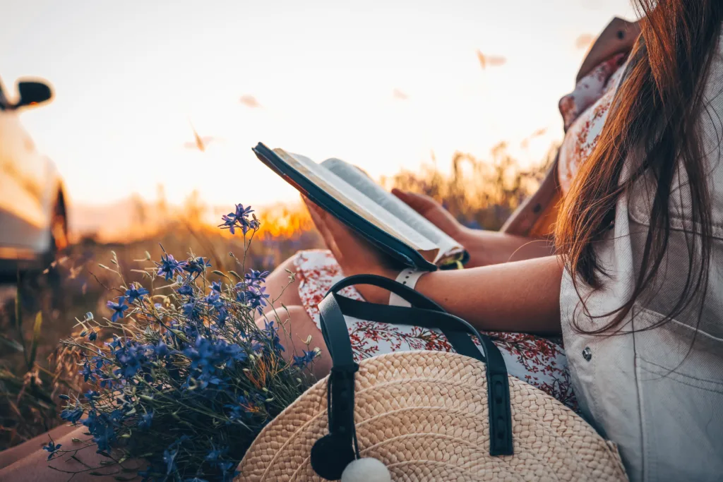 
Christian woman holds bible in her hands while she has a quiet time. Reading the Holy Bible in a field during beautiful sunset. Concept for faith, spirituality and religion. Peace, hope